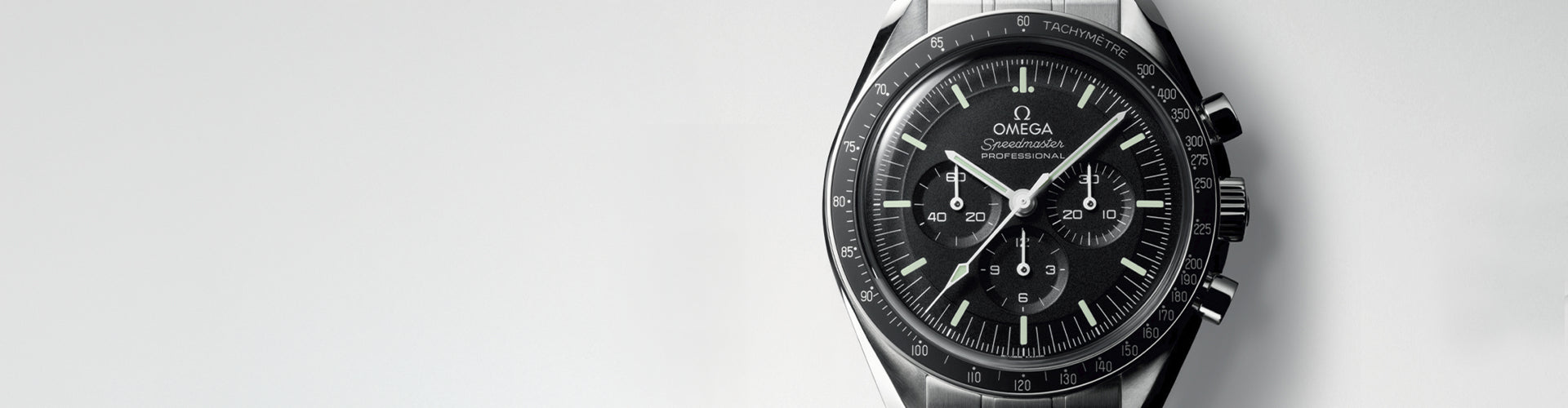 Omega Speedmaster watch with a black dial, black bezel, and a dark gunmetal-tone stainless steel case, shown on a light gray background.